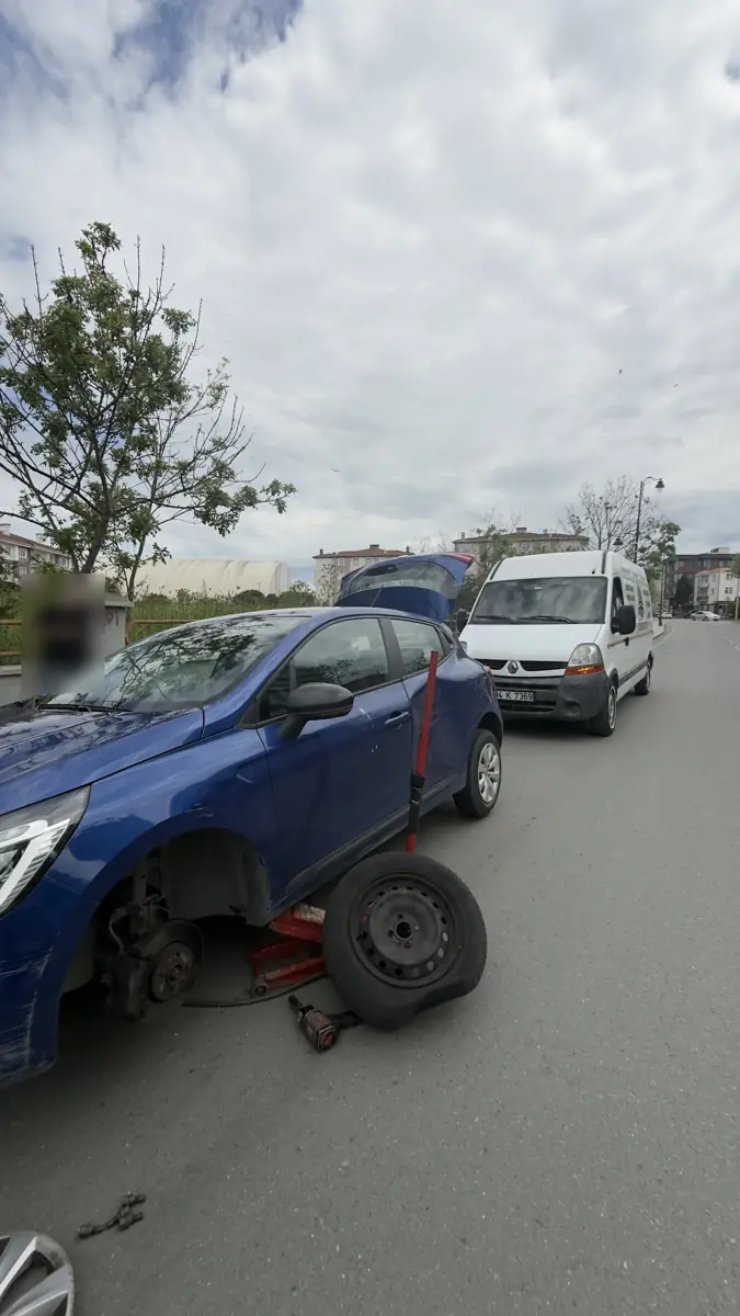 Şehir içinde yol kenarında lastiği sökülmüş mavi otomobil